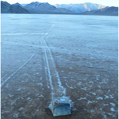 GPS-instrumented rock with its rock trail.The GPS unit with its battery pack is inserted into a cavity bored into the top of the rock. The GPS continuously logs its position after a switch is triggered by the stone moving away from a magnet set in the playa. The surface of the playa is frozen in this image, but the ice had melted or was floating when the trail formed. Image by Mike Hartmann.